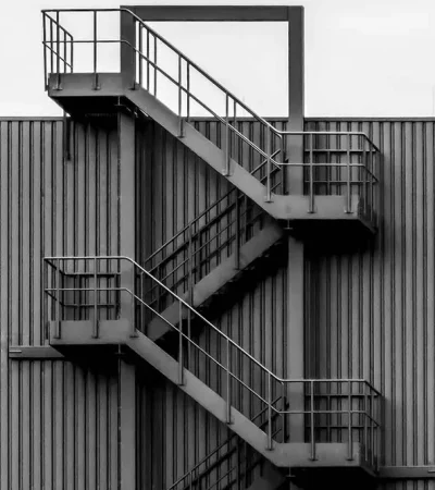 gray-metal-wall-with-spiral-stairs-clear-sky portr industrial staircase